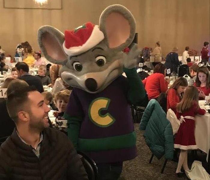 Chuck E. Cheese character waves to guests at breakfast