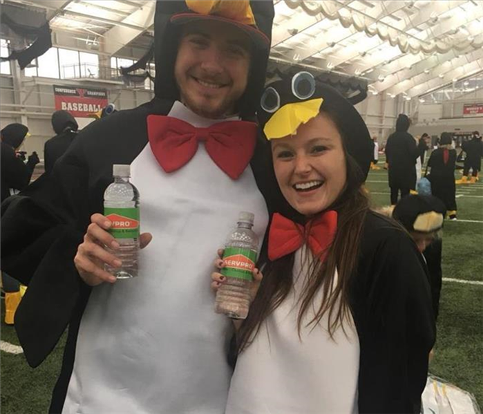 Photo of two people dressed like penguins holding SERVPRO water bottles