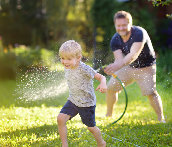 dad spraying son with hose