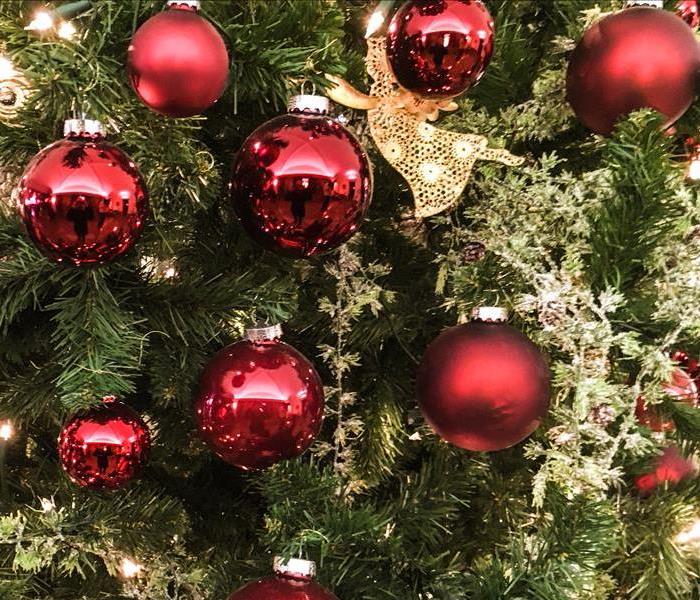 closeup of christmas tree with red bulbs hanging 