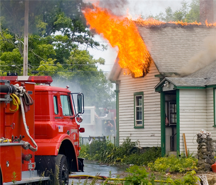 Firetruck next to a house on fire.