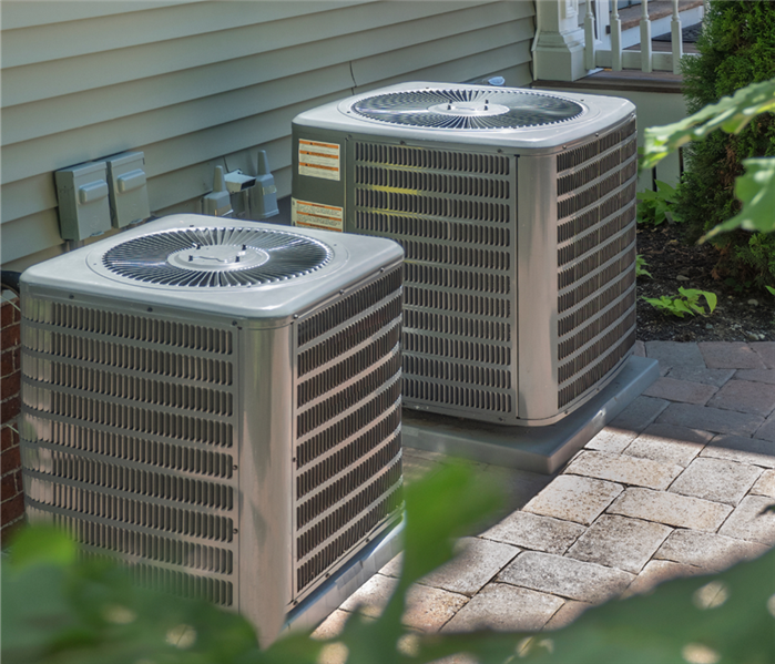 Two HVAC units sit outside of a house.